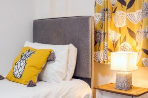 a bed with a yellow pillow and a table with a lamp at Royal Ashton Townhouse - Taunton in Taunton