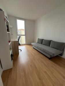 uma sala de estar com um sofá e um piso de madeira em Apartment in Calm Neighborhood em Eaubonne