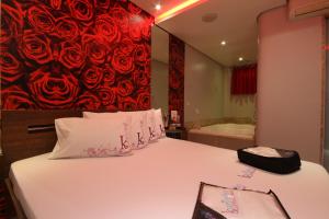 Karinho Hotel 4 في سانتو أندريه: غرفة نوم بسرير ولوحة ورد