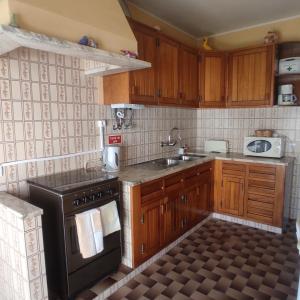 a kitchen with wooden cabinets and a black stove top oven at Casa Furtado in Burgau