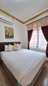 villa puncak bogor by GO puncak في Cikundul: غرفة نوم مع سرير أبيض كبير مع نافذة