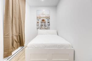 - une chambre blanche avec un lit et une fenêtre dans l'établissement Modern & Bright 3BR with Sofabed in Mile-End, à Montréal