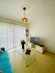 salon z niebieską kanapą i telewizorem w obiekcie Beach/ Pool Apartment Cadaques Bayahibe w mieście La Romana