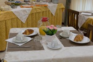 una mesa con platos de cruasanes y flores. en Albergo Bed and breakfast FLORIDA en Capo Rizzuto
