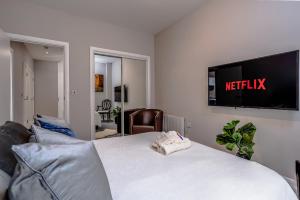 a bedroom with a bed with a television on the wall at Chic 1BR with Garden View in Central Bristol in Bristol