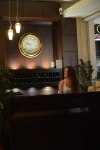 una mujer sentada frente a un reloj en una pared en Central Hotel en Paralia Katerinis