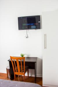 a desk with a chair and a television on a wall at BOTHA VILLA LODGE in Cape Town
