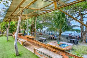 un restaurante en la playa con mesas y bancos en Atlantida Lodge Cahuita, en Cahuita