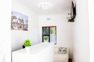 a white living room with a couch and a tv at Botha Villa Lodge Goodwood in Cape Town