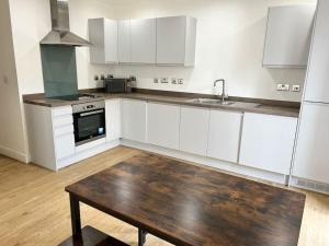 a kitchen with white cabinets and a wooden table at Lovely 2 bedroom Apartment in Central Manchester in Manchester