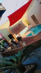 eine Terrasse mit Stühlen und einem Sonnenschirm neben einem Pool in der Unterkunft Pousada Recanto da Morada in Olímpia
