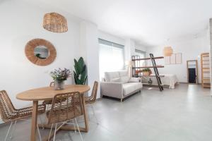 sala de estar con mesa, sillas y sofá en Tartessos Apartamentos 1 en Sevilla