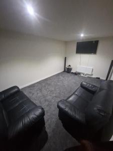 sala de estar con sofá de cuero y TV de pantalla plana en Guest Village, en Hull