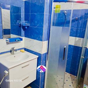 a blue tiled bathroom with a sink and a shower at Appartement à louer 180 m² sur la route nationale in Mérina