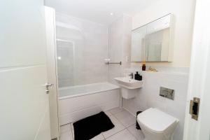 een witte badkamer met een toilet en een wastafel bij Stunning 4 bed house near stadium and green park in Reading