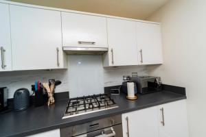 een keuken met witte kasten en een zwart aanrecht bij Stunning 4 bed house near stadium and green park in Reading