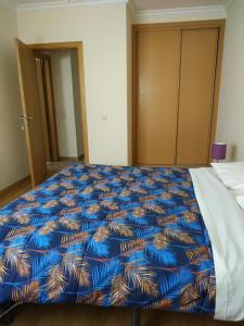 a bed in a room with a blue comforter at Edifice Ibérico in Albufeira