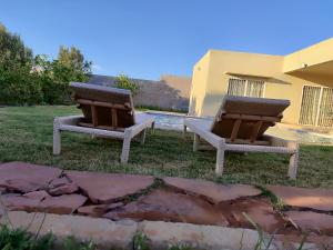two chairs sitting in the grass next to a building at ferme privé avec piscine in Safi