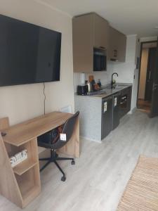 a kitchen with a desk with a television on the wall at Hermoso departamento nuevo en el corazón de Independencia in Santiago