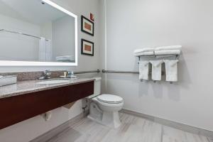 a bathroom with a toilet and a sink and a mirror at Comfort Suites Lombard/Addison in Lombard
