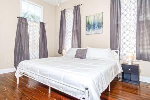 a white bed in a bedroom with wooden floors at Americana Cottage Closest Historic BnB to Benning in Columbus