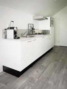 an empty kitchen with white cabinets and a sink at BEACHHOUSE VELUWEMEER in Strandnähe - mit extra großem Garten inkl Hallenbadnutzung in Hulshorst +17 photos