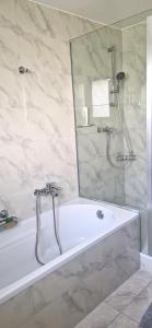 uma casa de banho com uma banheira e um chuveiro com um espelho. em Coeur du Léman em Saint-Legier-La Chiesaz