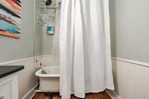 a bathroom with a white shower curtain and a sink at Mins from Downtown & Dining, Dauphin Darling 2 in Mobile