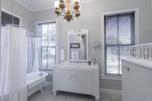 a white bathroom with a tub and a sink and a mirror at Mighty Mildred- Historic-Walkable-Mins to Riverwalk in Columbus