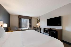 a hotel room with a large bed and a flat screen tv at Quality Inn University Area in Farmville