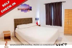 1 dormitorio con cama blanca y ventana en Rental Palhoça- Acomodações Residenciais, en Palhoça