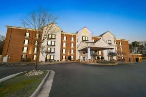 un grand bâtiment en briques avec un arbre devant lui dans l'établissement Comfort Suites Newport News Airport, à Newport News