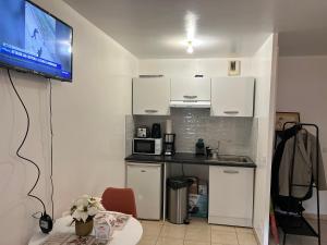 a kitchen with white cabinets and a tv on a wall at Studio à 2 pas du métro in Clichy