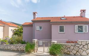 una casa rosa con una recinzione in pietra di fronte di Apartments Lila a Cres