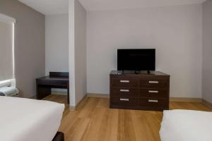 a bedroom with a tv on a dresser with a bed at Quality Suites Lake Charles Downtown in Lake Charles