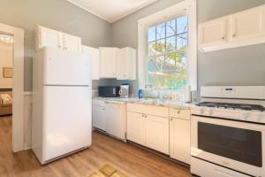 a kitchen with white cabinets and a white refrigerator at The Sunny Southern Manse Back Walk Downtown in Columbus