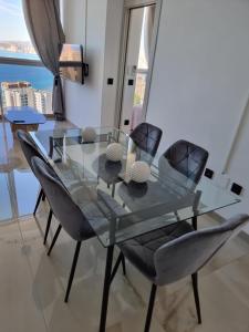 uma mesa de jantar em vidro e cadeiras com vista para a cidade em Cielo de Benidorm em Benidorm