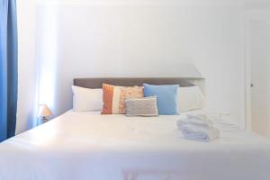 ein weißes Bett mit bunten Kissen darauf in der Unterkunft Heart of Downtown Craftsman Walk to Shops Dining in Columbus