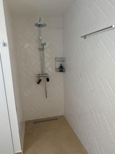 a shower in a bathroom with a white wall at L'orchidée de Montebello in Petit-Bourg