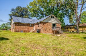 ein großes Backsteinhaus mit einer Veranda auf einem Feld in der Unterkunft 15 Mins to Downtown & Zoo Hawkins Mill Hideaway in Memphis