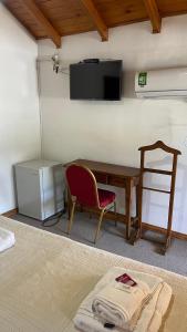 Cette chambre comprend un bureau, une chaise et une télévision. dans l'établissement Hostería Don Costa, à Chos Malal