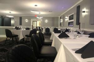 a dining room with white tables and black chairs at Inn on the Square, Ascend Hotel Collection in Greenwood