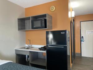 a kitchen with a black refrigerator and a sink at Suburban Studios Columbia Northwest in Columbia