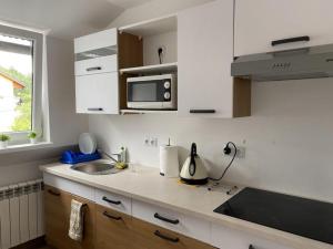 a white kitchen with a sink and a microwave at Pokoje gościnne u Faronow in Muszyna