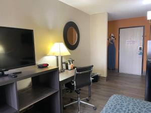 a hotel room with a desk with a television and a bed at Suburban Studios Columbia Northwest in Columbia