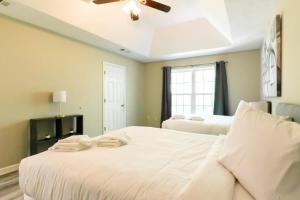 a bedroom with a large white bed with a ceiling fan at Minutes to Benning Two-Story Oasis Benning Bliss in Columbus