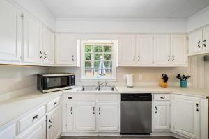 a kitchen with white cabinets and a sink and a window at 20 Mins to Downtown - Relaxing Rambler in Mobile