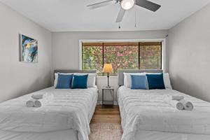 two beds in a white room with blue pillows at Minutes from Tiger Stadium South Campus Hideaway in Baton Rouge