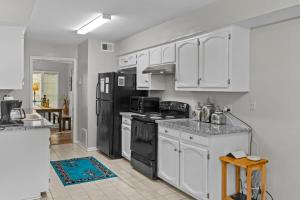 a kitchen with white cabinets and black appliances at Minutes from Tiger Stadium South Campus Hideaway in Baton Rouge