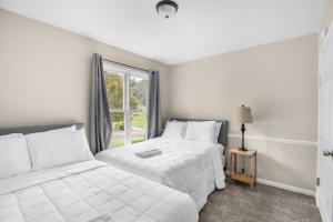 a white bedroom with two beds and a window at Two Kitchens Family Friendly in Forestdale in Birmingham